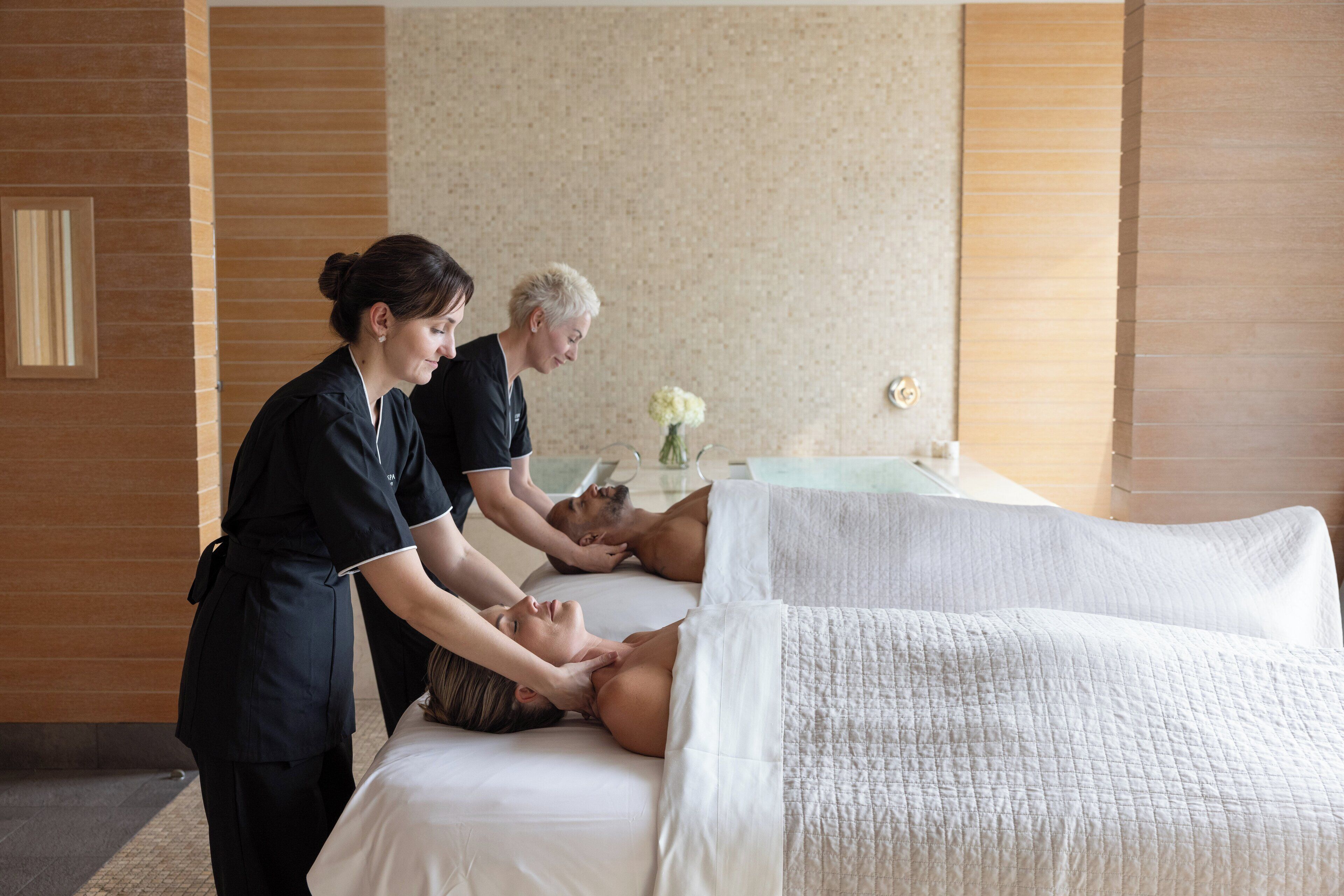 A massage therapy room with a massage table, a client receiving a back massage, and a therapist attending to the client.