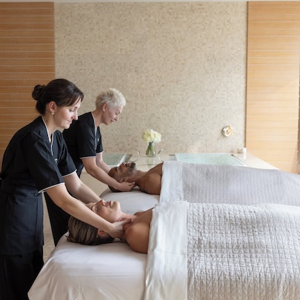 A massage therapy room with a massage table, a client receiving a back massage, and a therapist attending to the client.