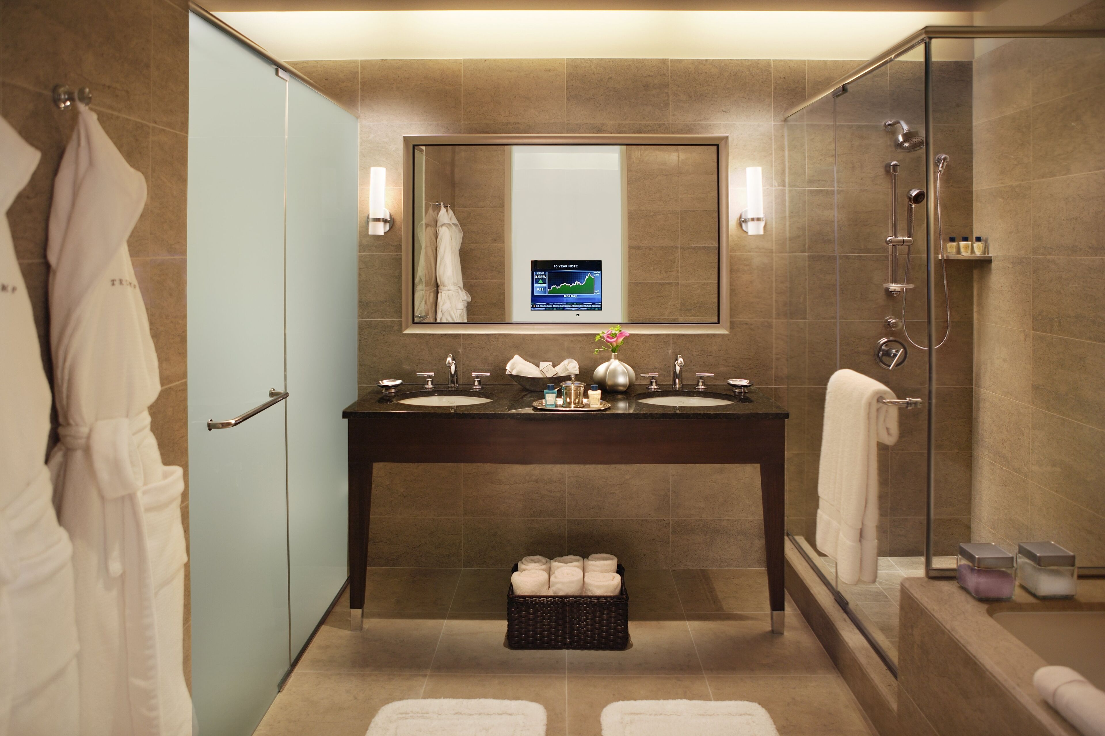 Un baño moderno con dos lavamanos, un espejo grande, una ducha y cabina de ducha con paredes de vidrio.