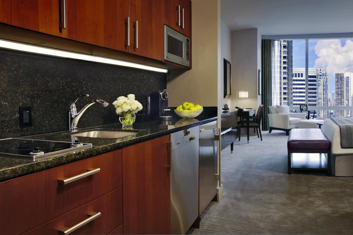 A modern kitchen with wooden cabinets, stainless steel appliances, and a bowl of fruit on the counter.
