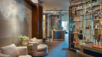 A modern lobby with a bar area, seating, and a decorative plant.