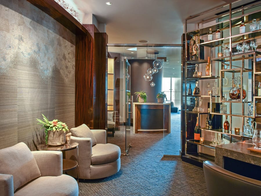 Un vestíbulo moderno con zona de bar, asientos y una planta decorativa.