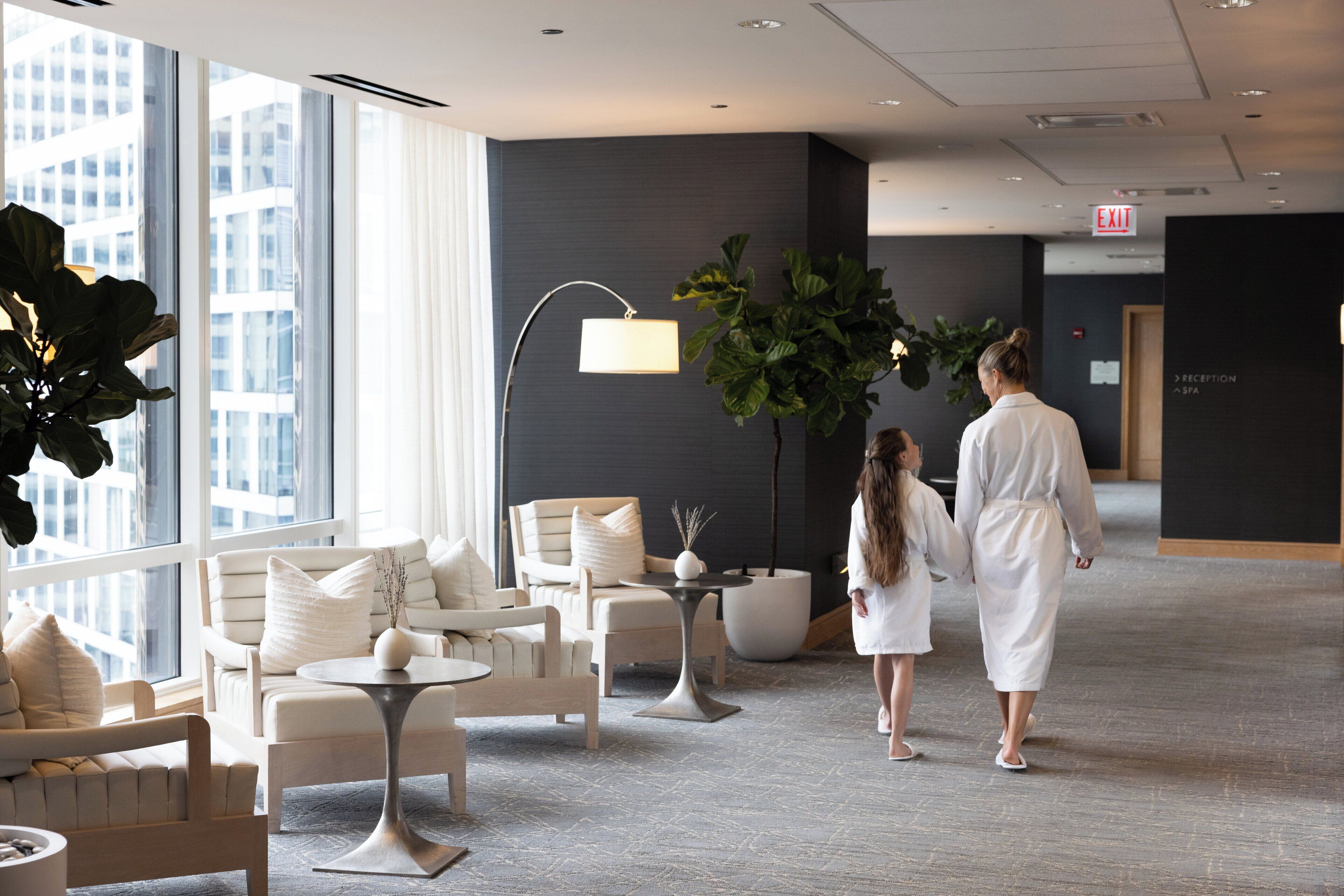 A modern hotel lobby with a reception area, seating arrangements, and large windows offering a view of the cityscape.
