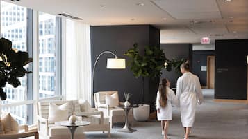 A modern hotel lobby with a reception area, seating arrangements, and large windows offering a view of the cityscape.