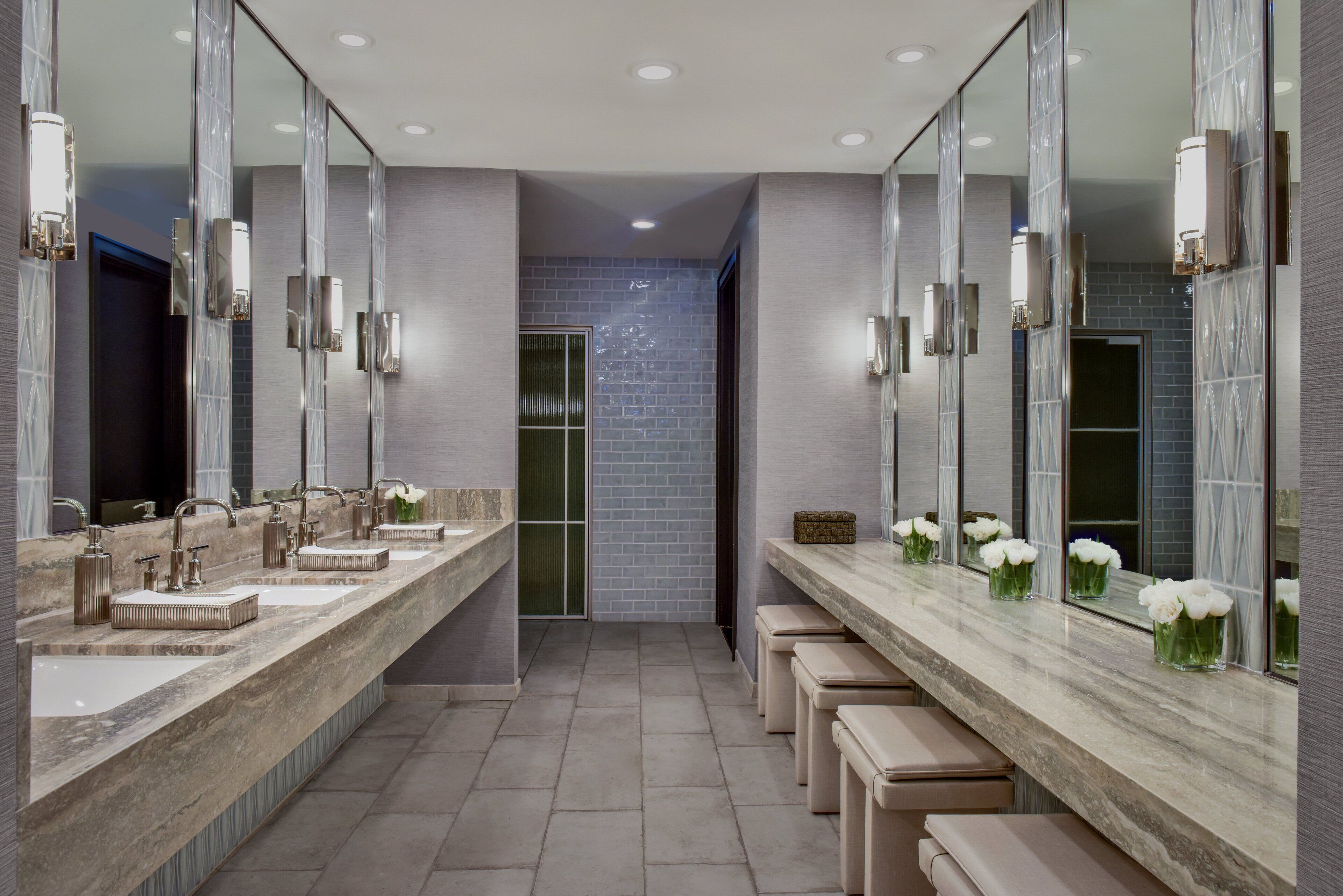 Une salle de bain moderne avec trois lavabos, de grands miroirs et des bancs.