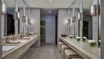 Une salle de bain moderne avec trois lavabos, de grands miroirs et des bancs.