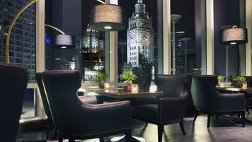 Un comedor moderno con sillas de cuero negro, una mesa redonda y grandes ventanales con vistas a una torre del reloj.