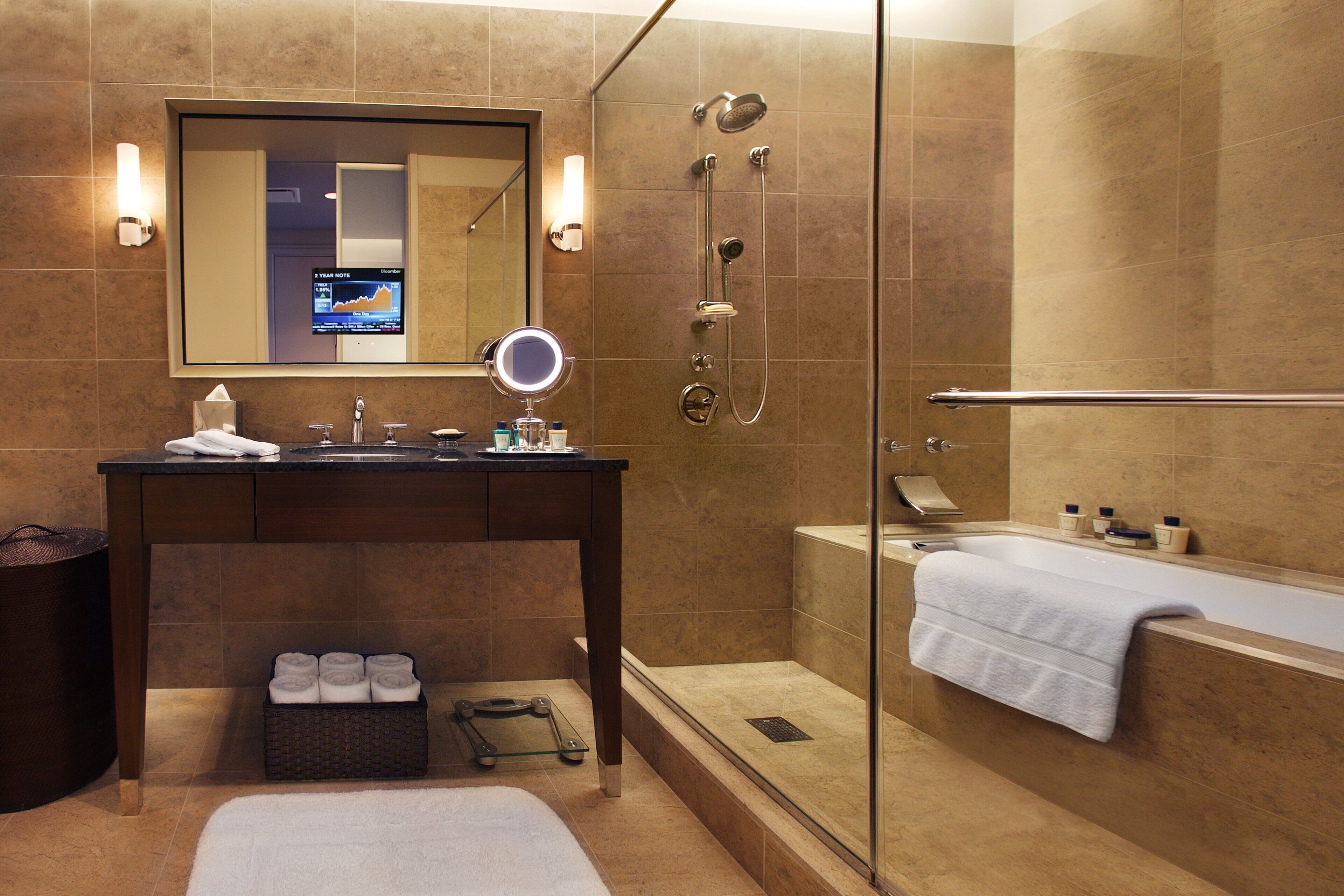 A modern bathroom with a glass-enclosed shower, a vanity with a mirror, and a bathtub with a towel.