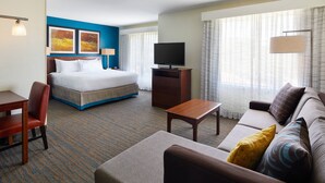 Una habitación de hotel con una cama, un sofá, un escritorio y un televisor.