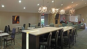Un restaurante con una barra alargada, varias zonas de estar y candelabros colgantes.