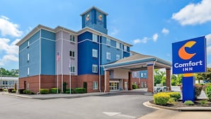 A Comfort Inn hotel with a blue and red exterior, American flags, and a clear sky. - Comfort Inn Emporia (Emporia)