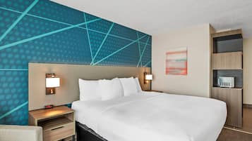 A hotel room with a large bed, two bedside tables with lamps, a wall-mounted TV, and a built-in shelving unit.