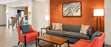 A modern living room with a sofa, two armchairs, a coffee table, and a painting on the wall.