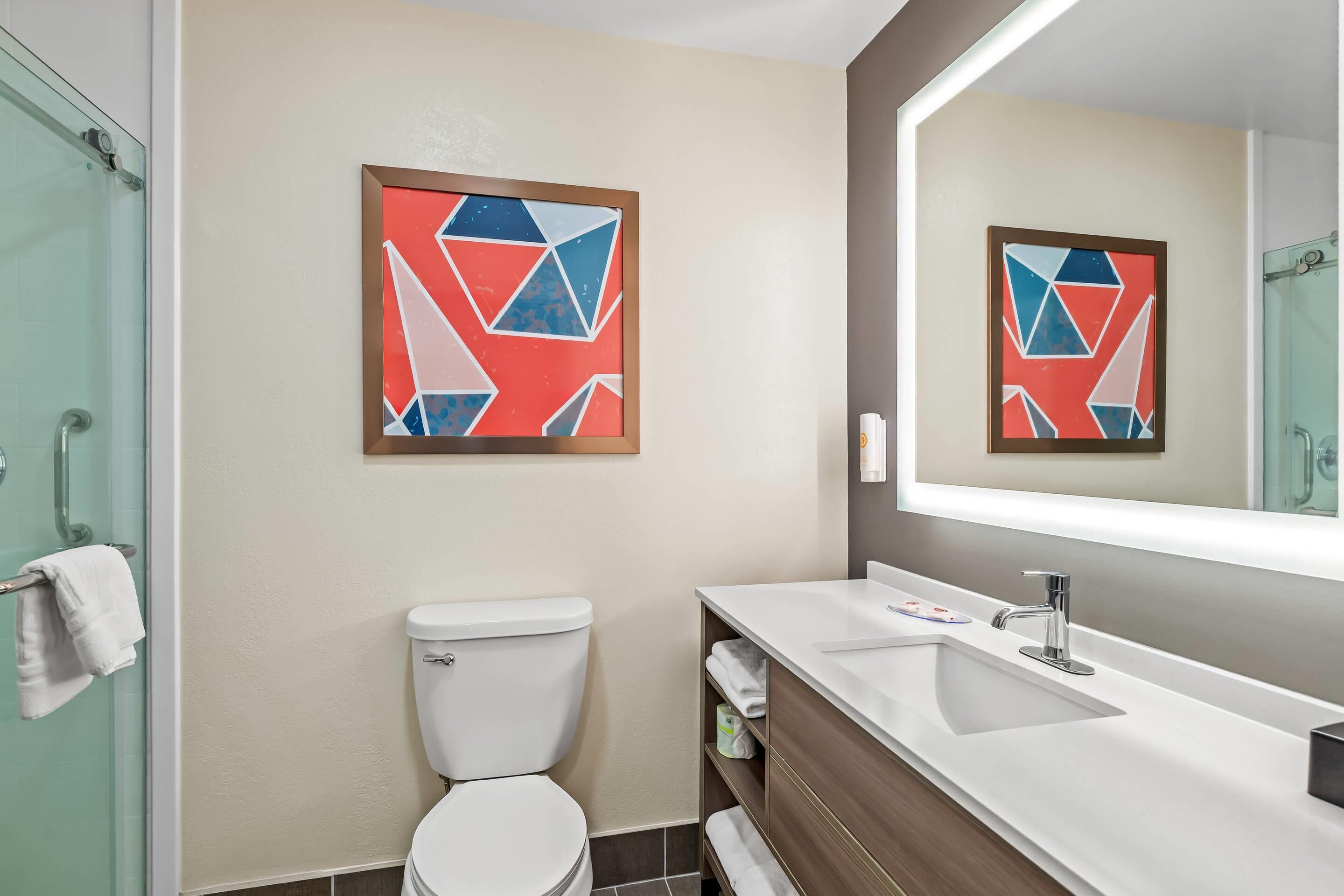 A modern bathroom with a toilet, sink, and glass shower enclosure.