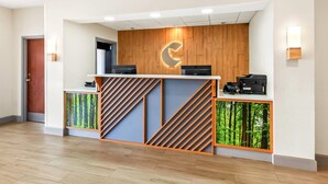 A reception desk with a wooden panel design, a logo, and two printers. - Comfort Inn Emporia (Emporia)
