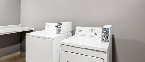 A laundry area with two white Whirlpool washers and a countertop.
