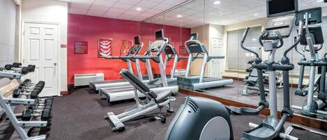 A gym with treadmills, weight machines, and dumbbells.
