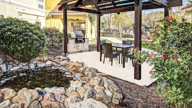 Un patio al aire libre con una pérgola, un hogar a leña de piedra y una parrilla.