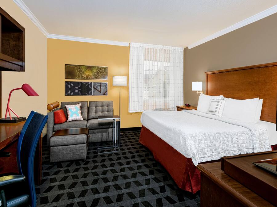 Habitación de hotel con cama, escritorio, silla, sofá y televisión.