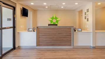 A reception area with a wooden reception desk, a mounted television, and a green wall decoration.