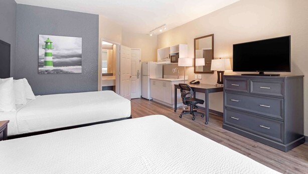 A hotel room with two beds, a desk, a television, a mirror, and a kitchenette. - Extended Stay America Suites - Baytown (Baytown)