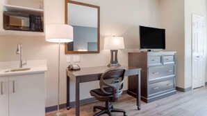 A hotel room with a desk, two lamps, a television, a mirror, a microwave, a telephone, and a cabinet. - Extended Stay America Suites - Baytown (Baytown)
