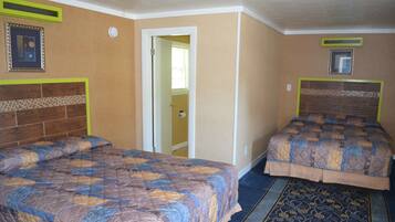 A hotel room with two beds, a patterned carpet, and a door leading to a bathroom.