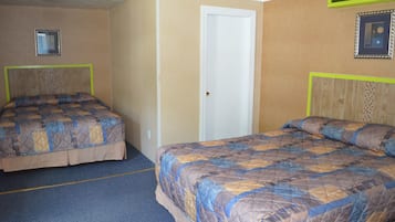 Quarto de hotel com duas camas, uma porta e um espelho na parede.
