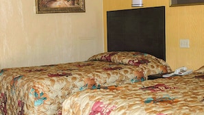 A hotel room with two beds, a headboard, a wall-mounted telephone, and a painting. - Charles Wesley Motor Lodge (Broken Bow)