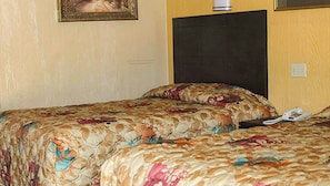 A hotel room with two beds, a headboard, a wall-mounted telephone, and a painting. - Charles Wesley Motor Lodge (Broken Bow)