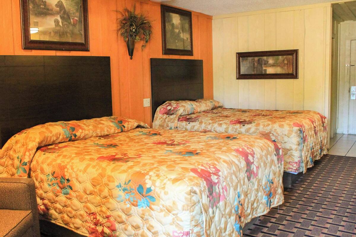 Ein Zimmer mit zwei Betten, einem Sessel und einer Tür.