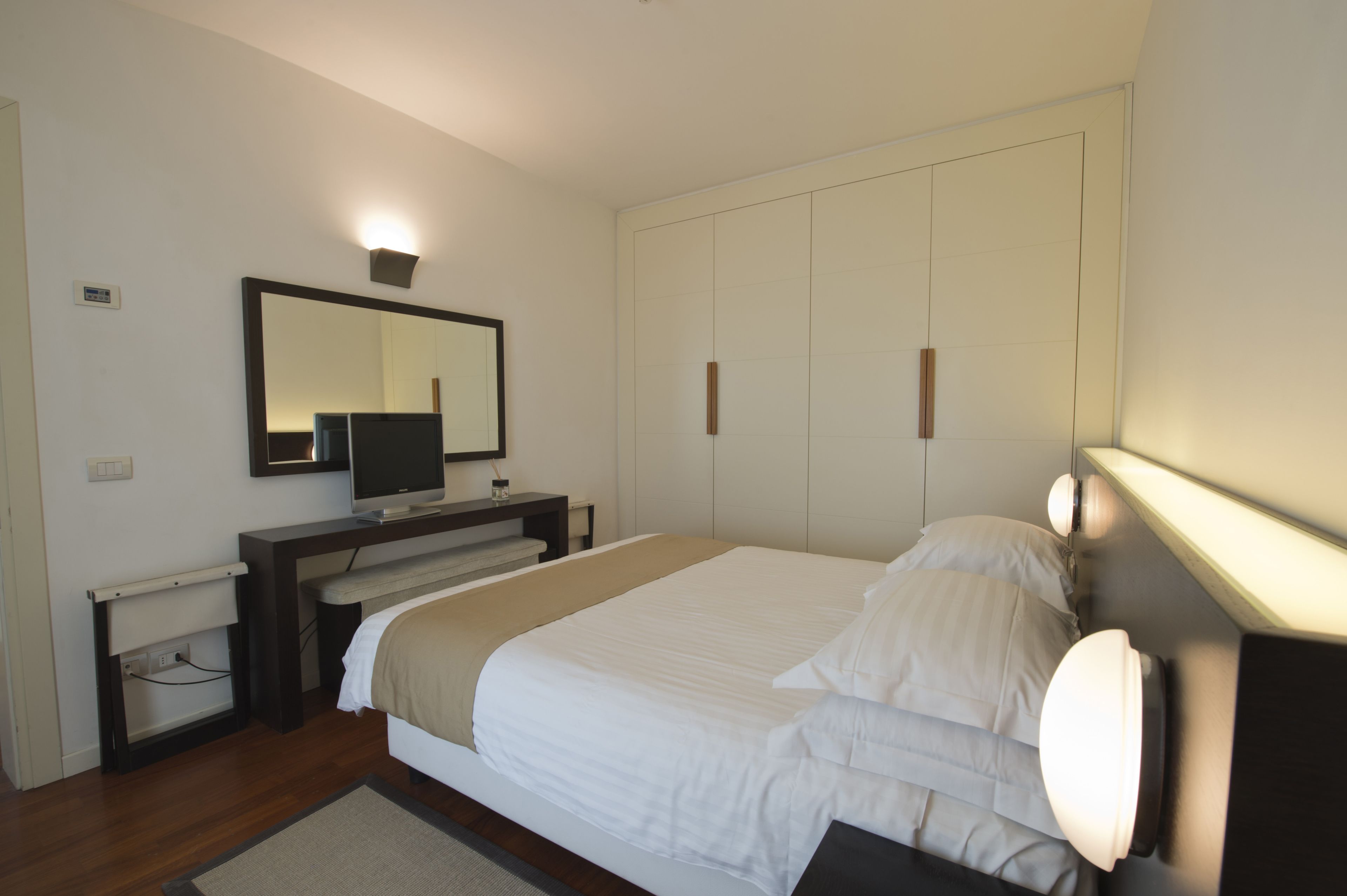 Una camera da letto con un letto, una TV, un armadio e uno specchio.