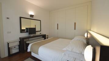 Una camera da letto con un letto, una TV, un armadio e uno specchio.