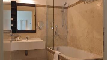 Un baño moderno con ducha de vidrio, bañera independiente y tocador con espejo.