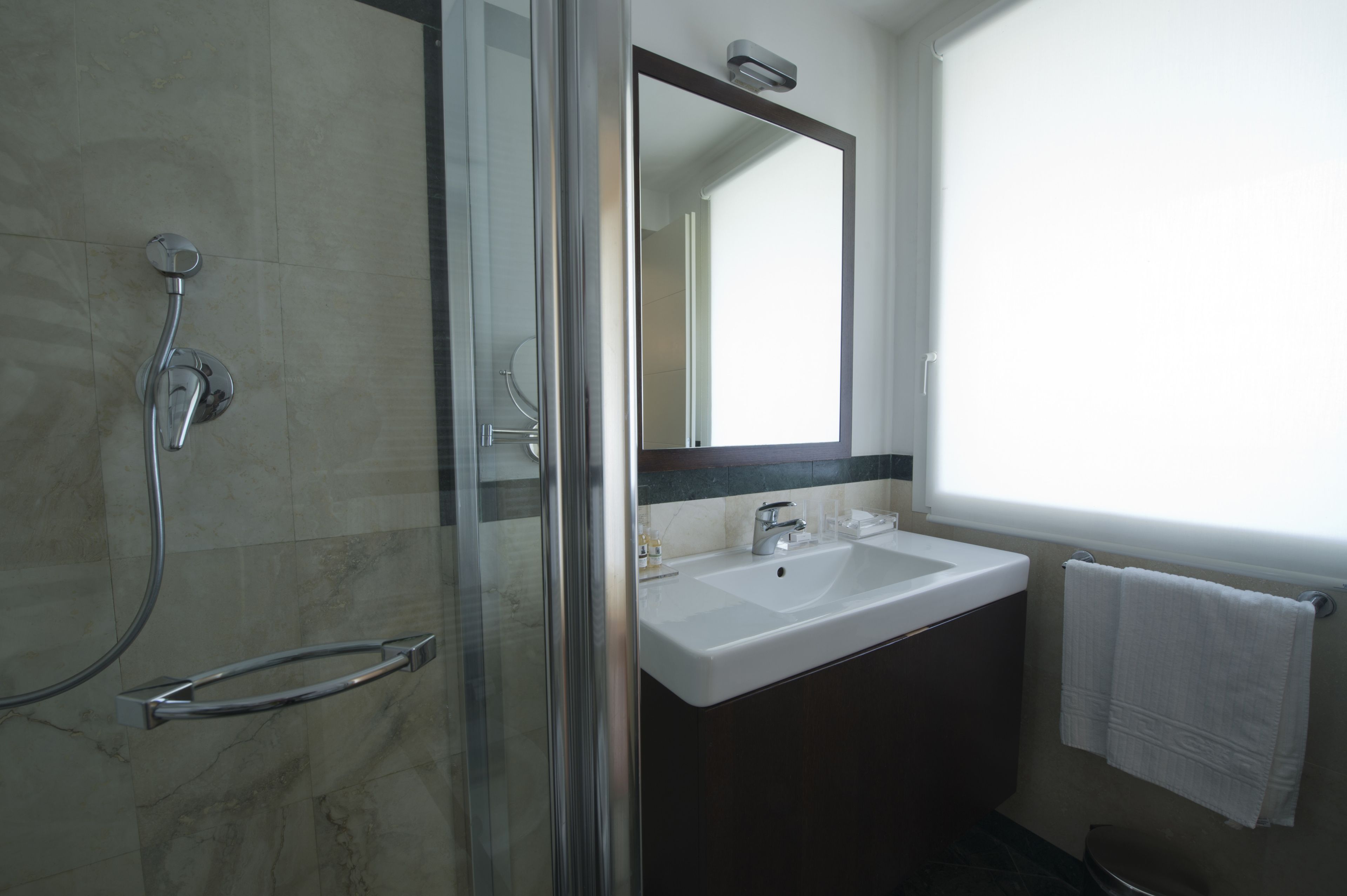 A bathroom with a glass shower enclosure, a white sink, and a large mirror.