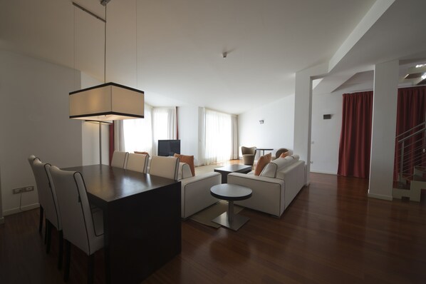 A modern living room with a dining area, a sofa set, a coffee table, and a TV.
