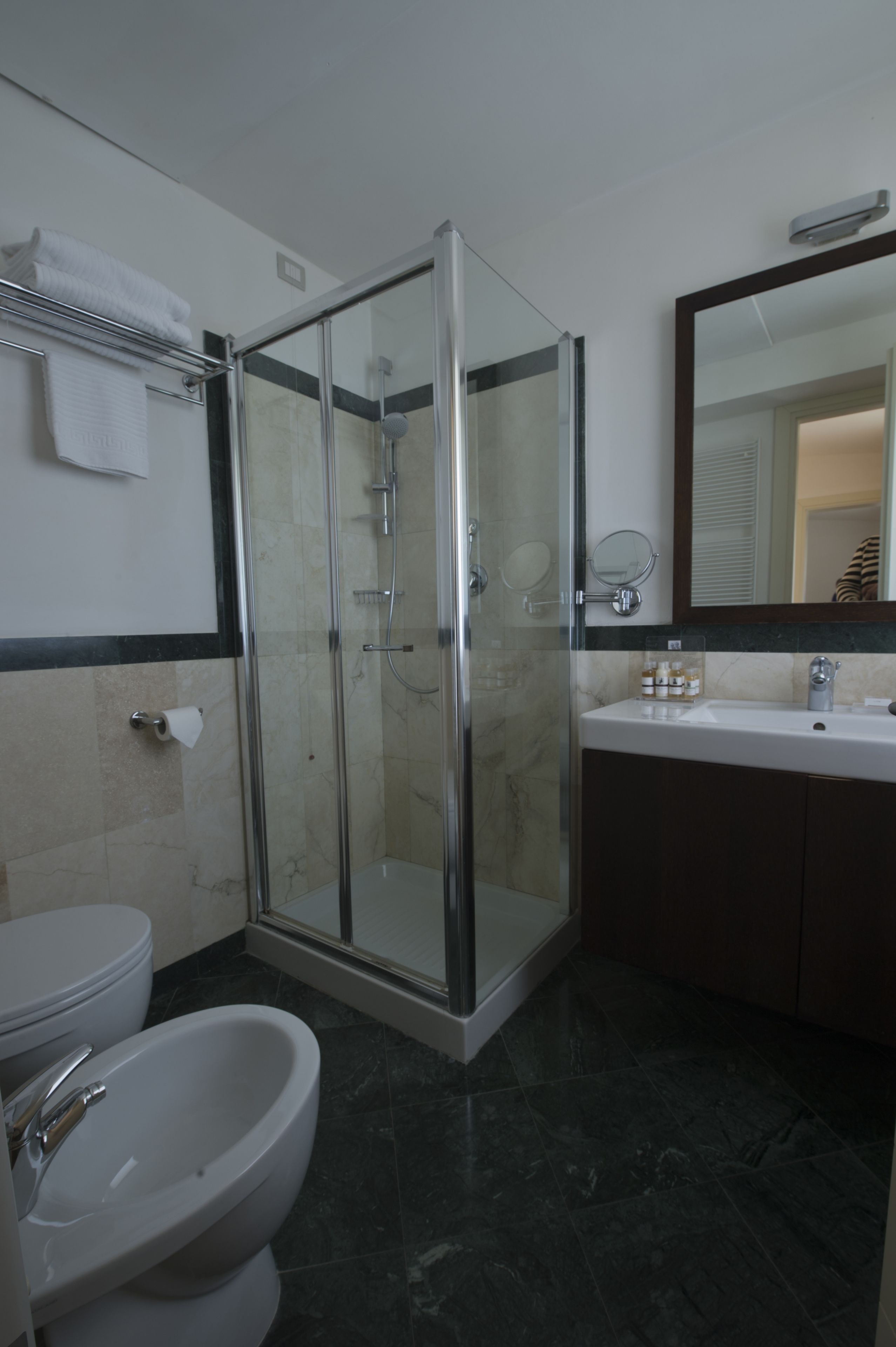 Une salle de bain moderne avec une douche à parois de verre, un lavabo blanc et un grand miroir.