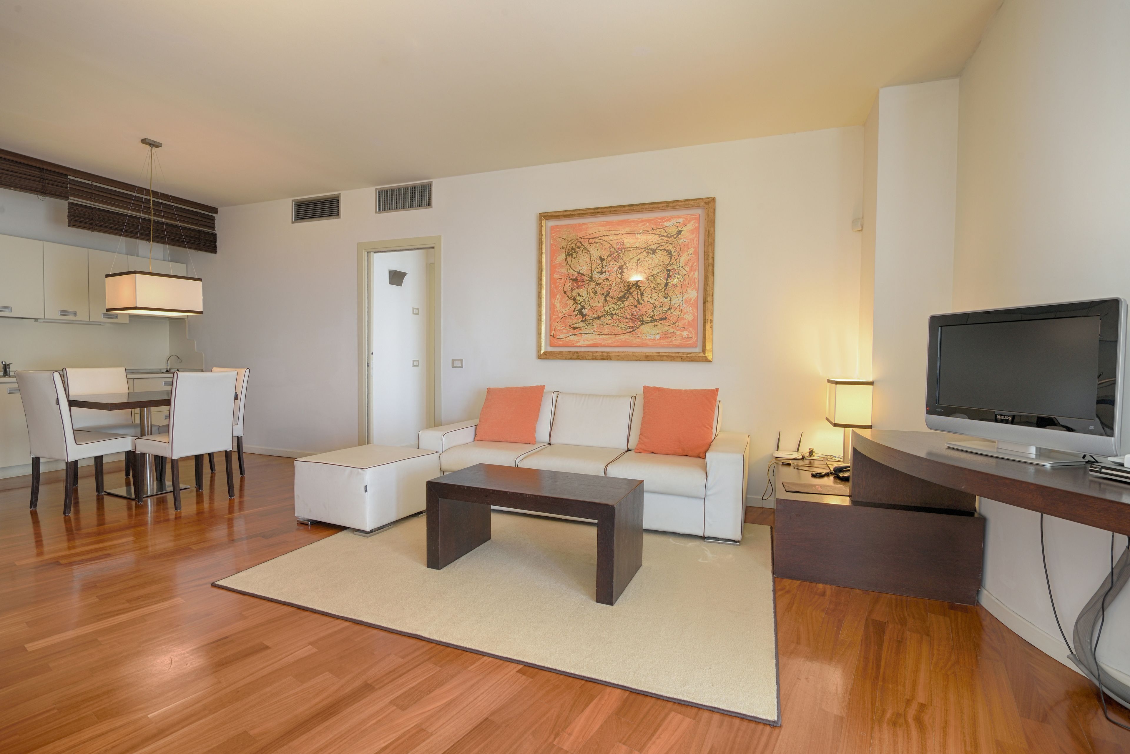 A modern living room with a sofa, coffee table, TV, and a painting on the wall.
