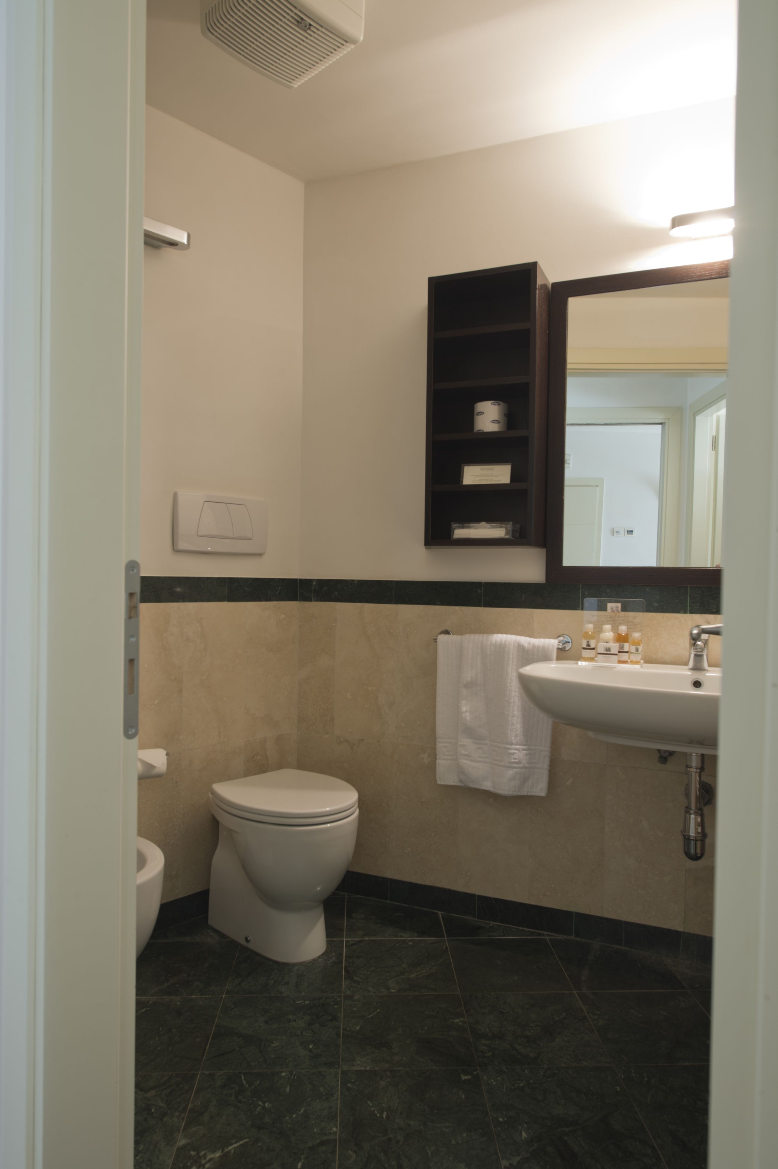 Un baño con inodoro, lavamanos y espejo.