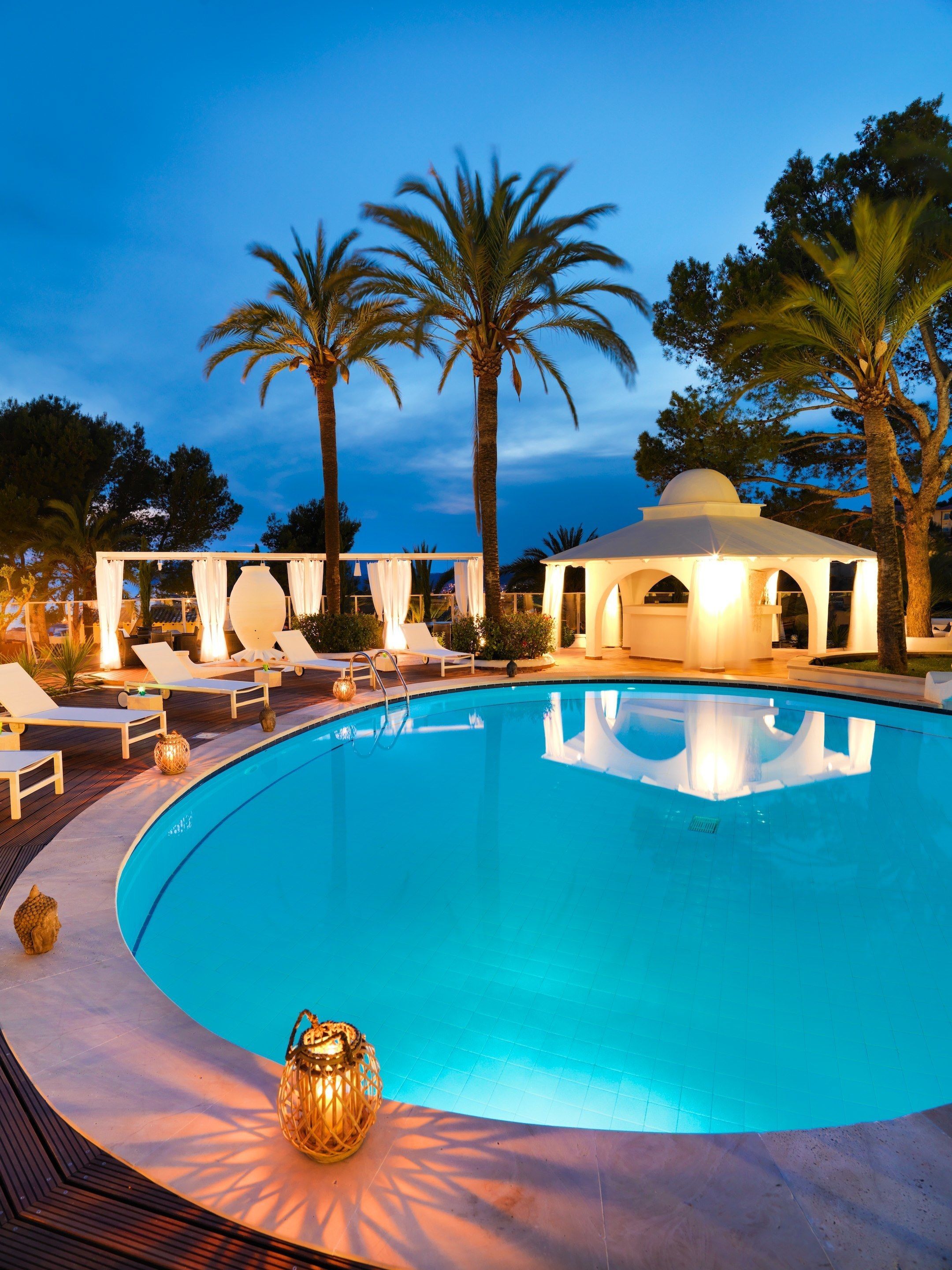 A pool area with lounge chairs and a gazebo.