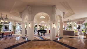 A grand lobby with marble flooring, a grand piano, and a large chandelier. - Hilton Mallorca Galatzo (Calvia)