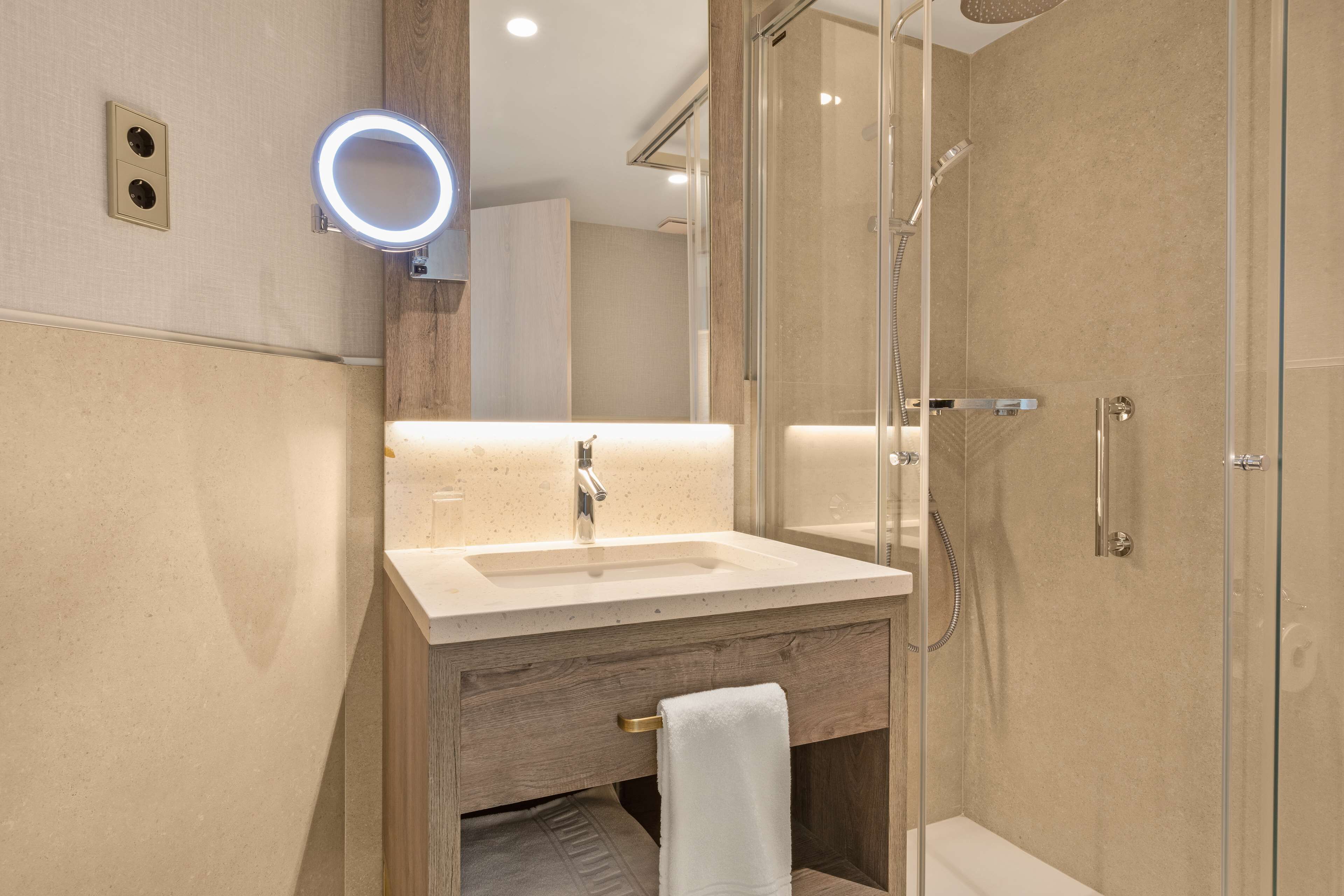 Une salle de bain moderne avec un lavabo, un miroir et une douche à parois en verre.
