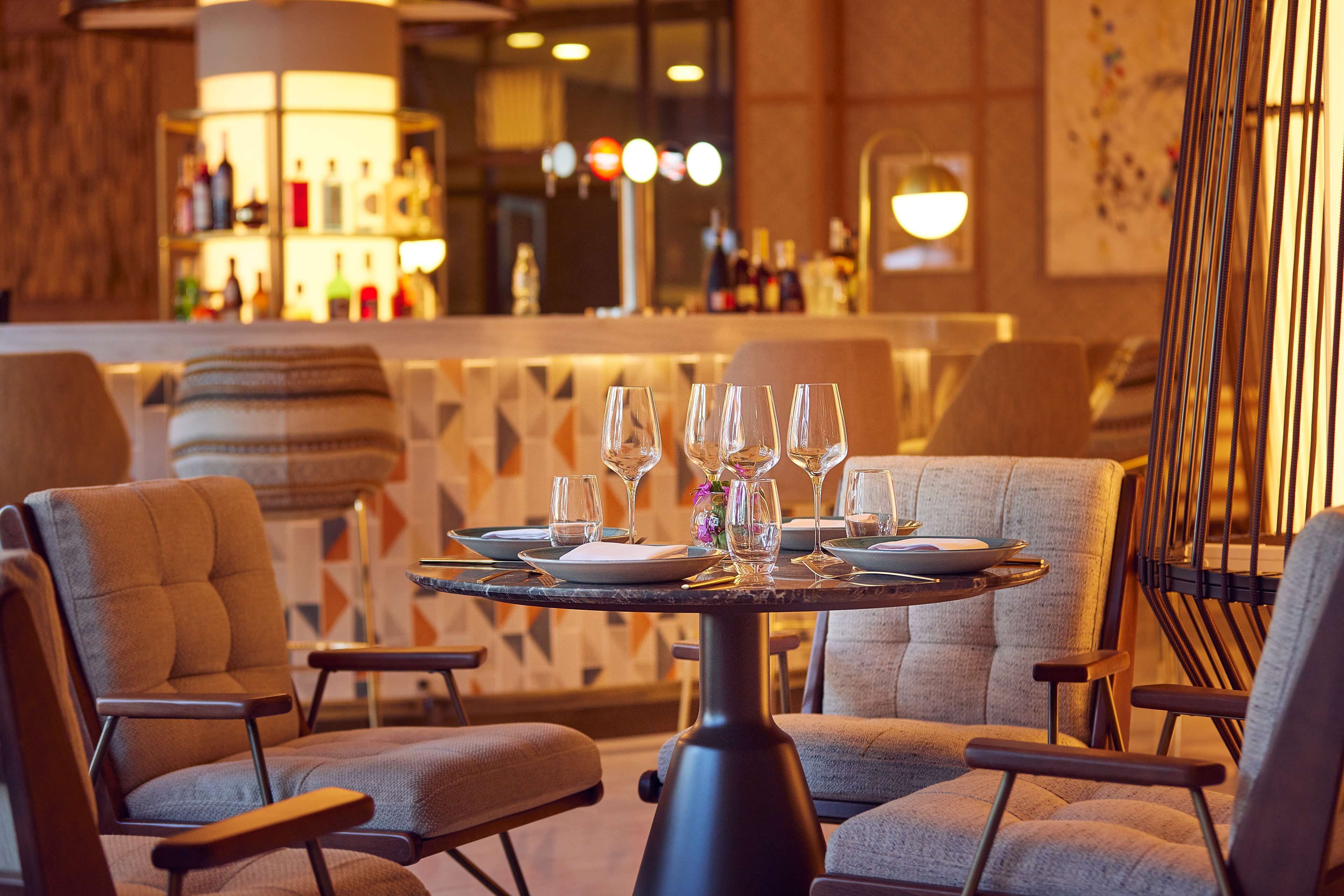 A dining area with a round table set for four, surrounded by upholstered chairs.