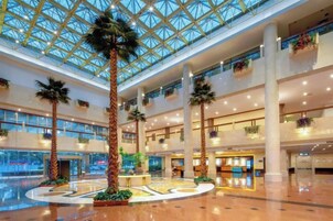 Un amplio atrium con techo alto y un área circular central con palmeras.