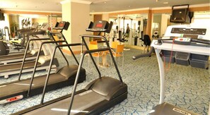 A gym with treadmills, exercise bikes, and a rowing machine. - Regency Hotel (Shantou)