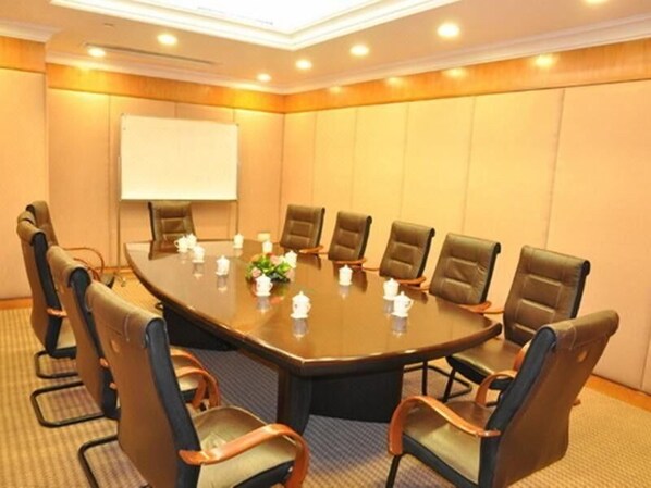 A conference room with a large oval table, eight chairs, a whiteboard, and a floral centerpiece.