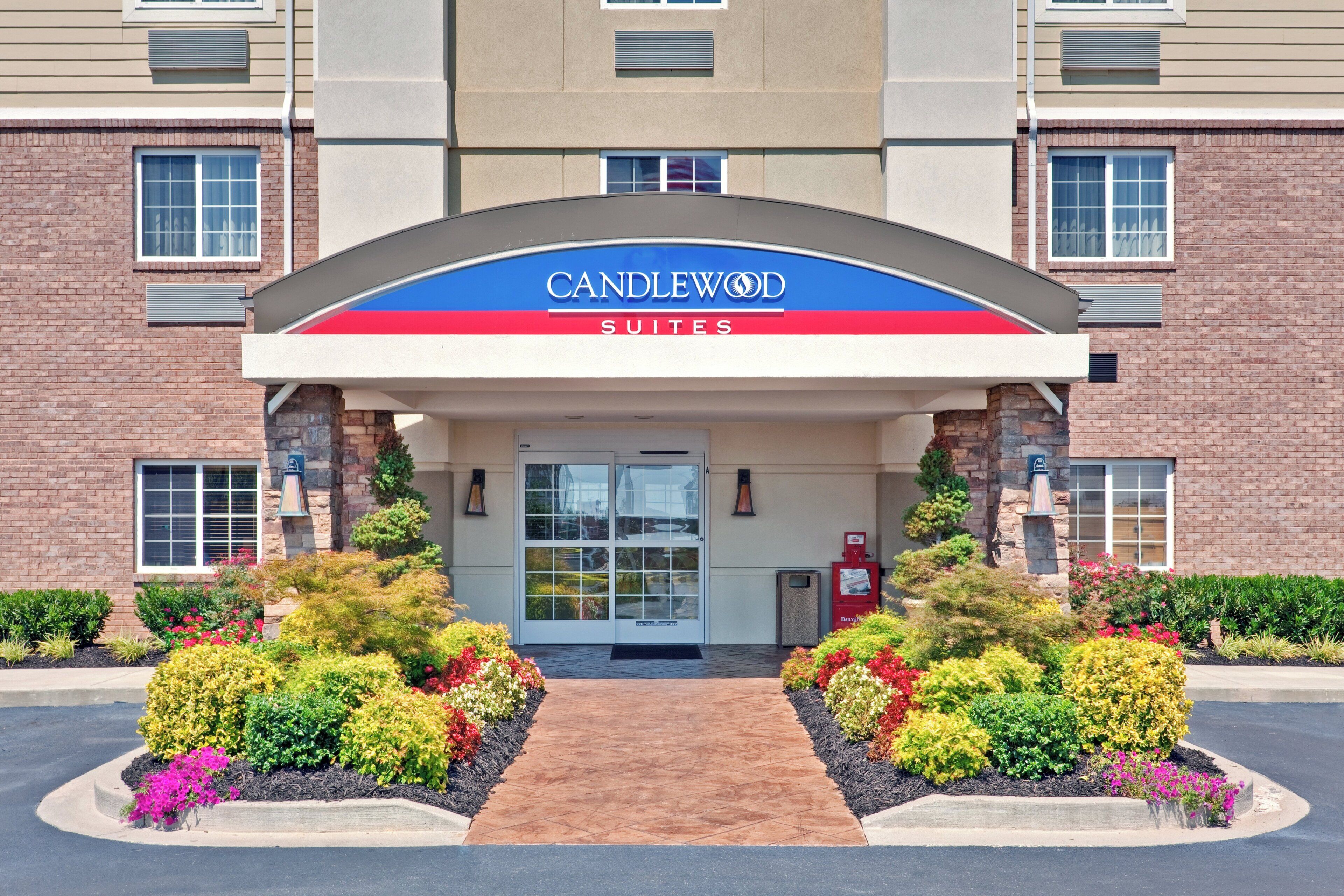 Entrada de hotel com uma placa indicando 'CANDLEWOOD SUITES'.