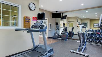 Un gimnasio con cintas de correr, bicicletas estáticas y máquinas de pesas.