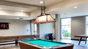 A pool table in a room with wooden flooring, a hanging lamp, and a television on the wall. - Candlewood Suites Bowling Green by IHG (Bowling Green)