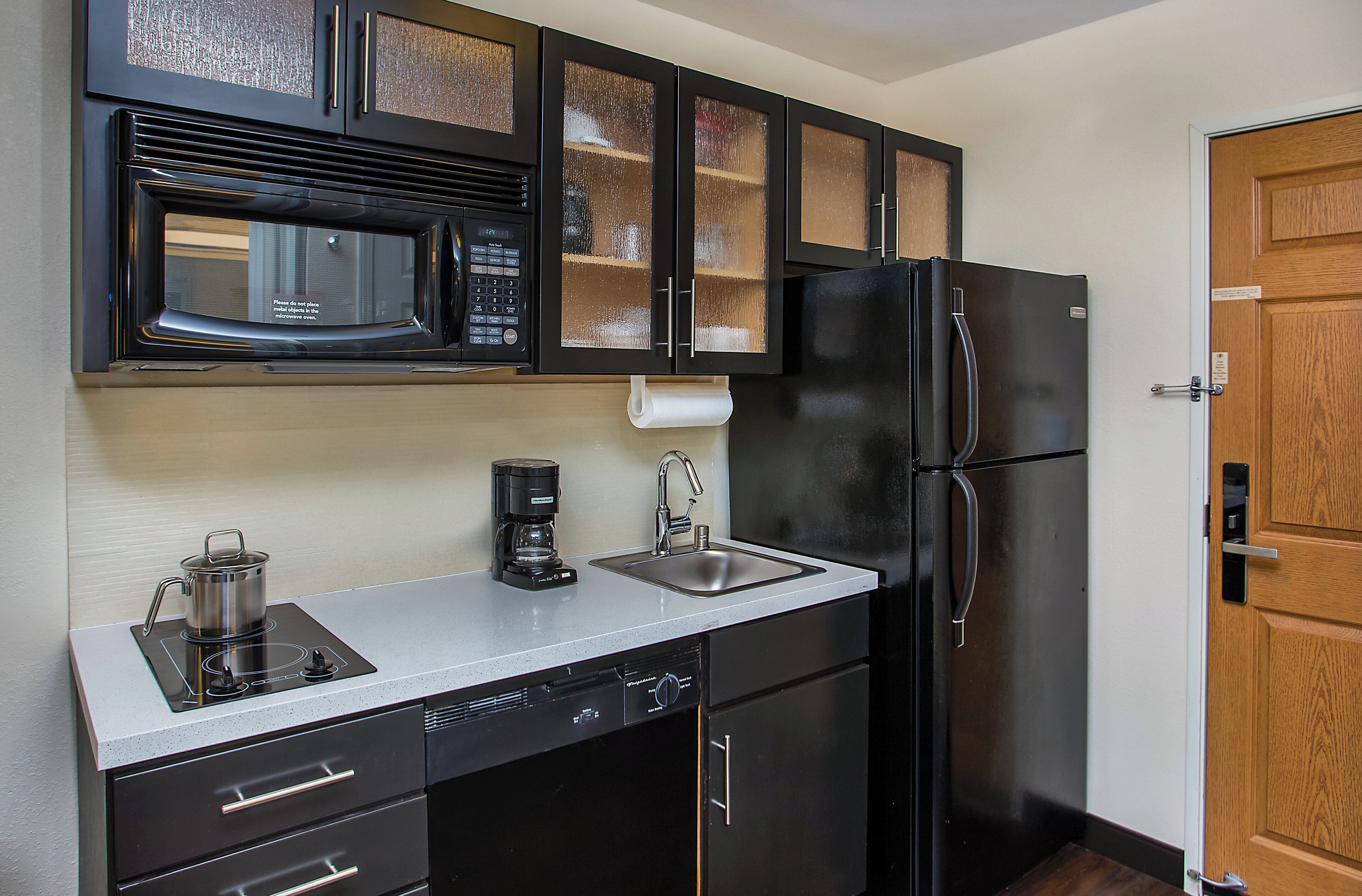 Cocina compacta con microondas, cafetera y refrigerador.